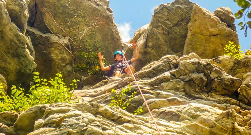 a student waves from above while rock climbing near DC